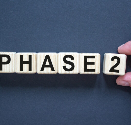 Time for Phase 2. Hand holds a cube with number '2'. Word 'Phase 2'. Beautiful black background. Business concept. Copy space.