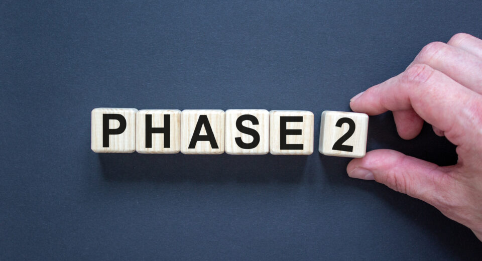 Time for Phase 2. Hand holds a cube with number '2'. Word 'Phase 2'. Beautiful black background. Business concept. Copy space.