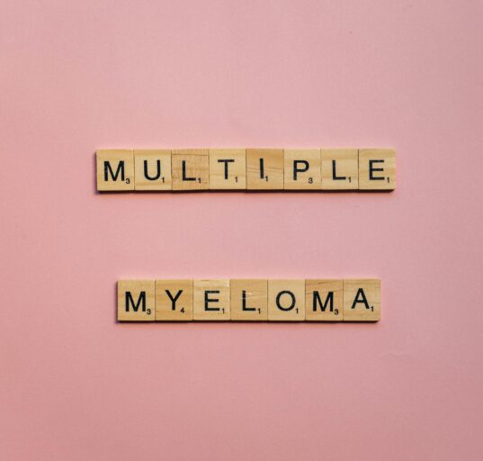 pink back ground , multiple myeloma spelled out in wooden blocks