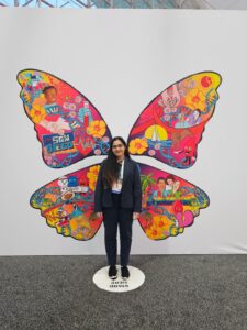 Maha Hameed in front of a colorful butterfly. 